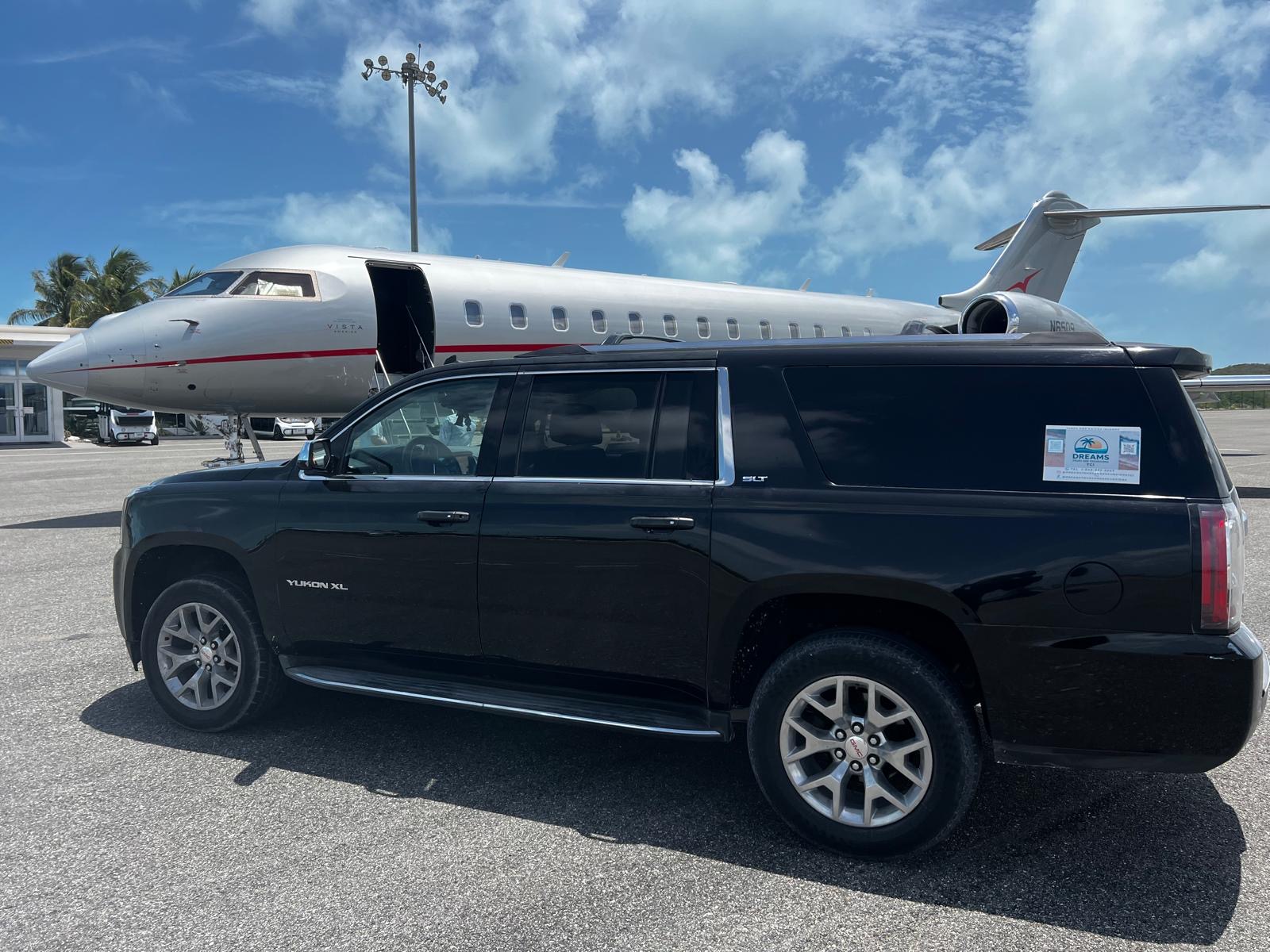 Dreams Tours black GMC Yukon XL beside a private jet at the airport in Turks and Caicos